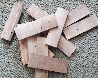 May include: A pile of eight light brown wooden boards with rough edges. The boards are arranged in a random pattern, with some overlapping.