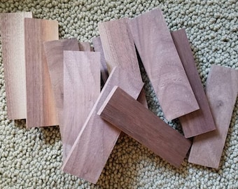 May include: A collection of eight wooden planks, all in various shades of brown, arranged on a light green carpet.