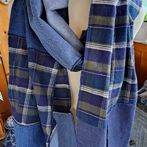 Może przedstawiać: Szalik w niebiesko-zieloną kratę wykonany z odzyskanego denimu i flaneli. Szalik jest zawiązany wokół drewnianego manekina.