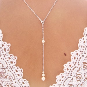 May include: A silver chain necklace with three white pearls hanging from it. The necklace is on a model wearing a white lace top.