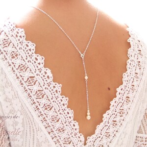 May include: A silver back necklace with three small pearl accents. The necklace is worn by a model with a white lace top.