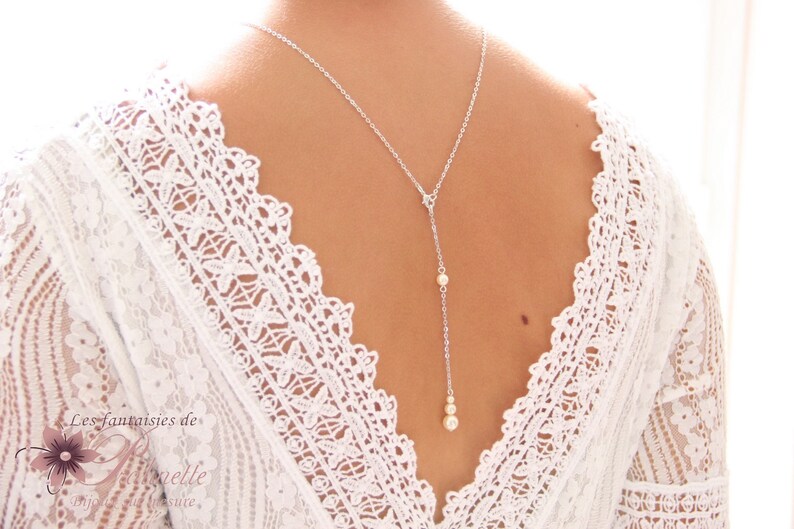 May include: A silver back necklace with three small pearl accents. The necklace is worn by a model with a white lace top.