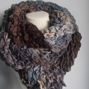 以下が含まれることがあります： 茶色、青、ベージュのニット製の無限ループのスカーフで、フリルのような質感です。