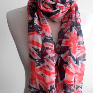 Puede incluir: Una bufanda con estampado geométrico rojo, blanco y azul. La bufanda está hecha de un tejido ligero y es perfecta para añadir un toque de color a cualquier atuendo.