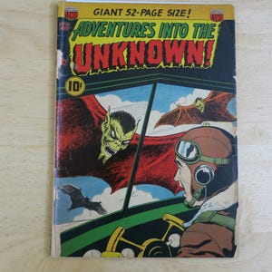 May include: Vintage comic book cover titled "Adventures Into The Unknown!" featuring a pilot in a cockpit, a green-faced demon, and bats. The cover is predominantly black, red, and yellow, with the price of 10 cents displayed.