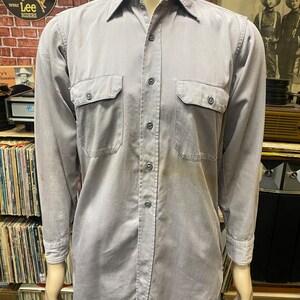 May include: A gray long-sleeved work shirt with two chest pockets and a button-down collar.