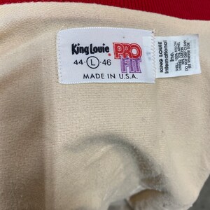 May include: A white tag with the text "King Louie International Inc." and "Pro Fit" in purple. The tag also includes the size "44-L-46" and the text "Made in U.S.A."