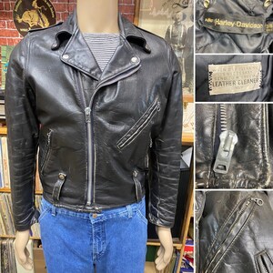 May include: A black leather motorcycle jacket with a zipper closure and multiple pockets. The jacket has a label that reads "ANF Harley-Davidson 38" and a tag that says "When dry cleaning is necessary send to a special leather cleaner only."