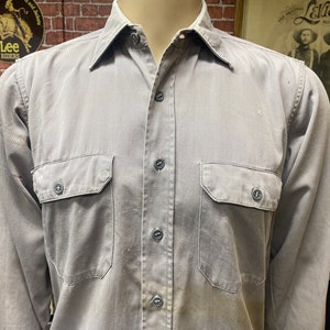 May include: A gray long-sleeved work shirt with two chest pockets and button closure.