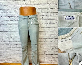 May include: Light blue Levi's Sta-Prest pants with a button fly, metal zipper, and a white interior label reading Levi's Sta-Prest. The care tag indicates a waist size of 32 inches and a length of 30 inches. The pants feature a classic cut.