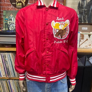 May include: Red satin bomber jacket with white and red striped trim. The jacket has a button closure and a large embroidered patch on the left chest featuring a moose and the text "Loyal Order of Moose" and "Pap Prelate 82-8".