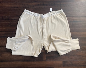May include: A pair of off-white thermal underwear with a button fly. The underwear has a ribbed texture and is made of a soft, comfortable material.