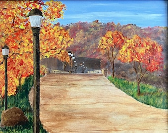 Può includere: Un dipinto che rappresenta un sentiero fiancheggiato da alberi con colori autunnali, che conduce a un ponte con lampioni. Il sentiero è pavimentato e gli alberi sono un mix di arancione, giallo e rosso.