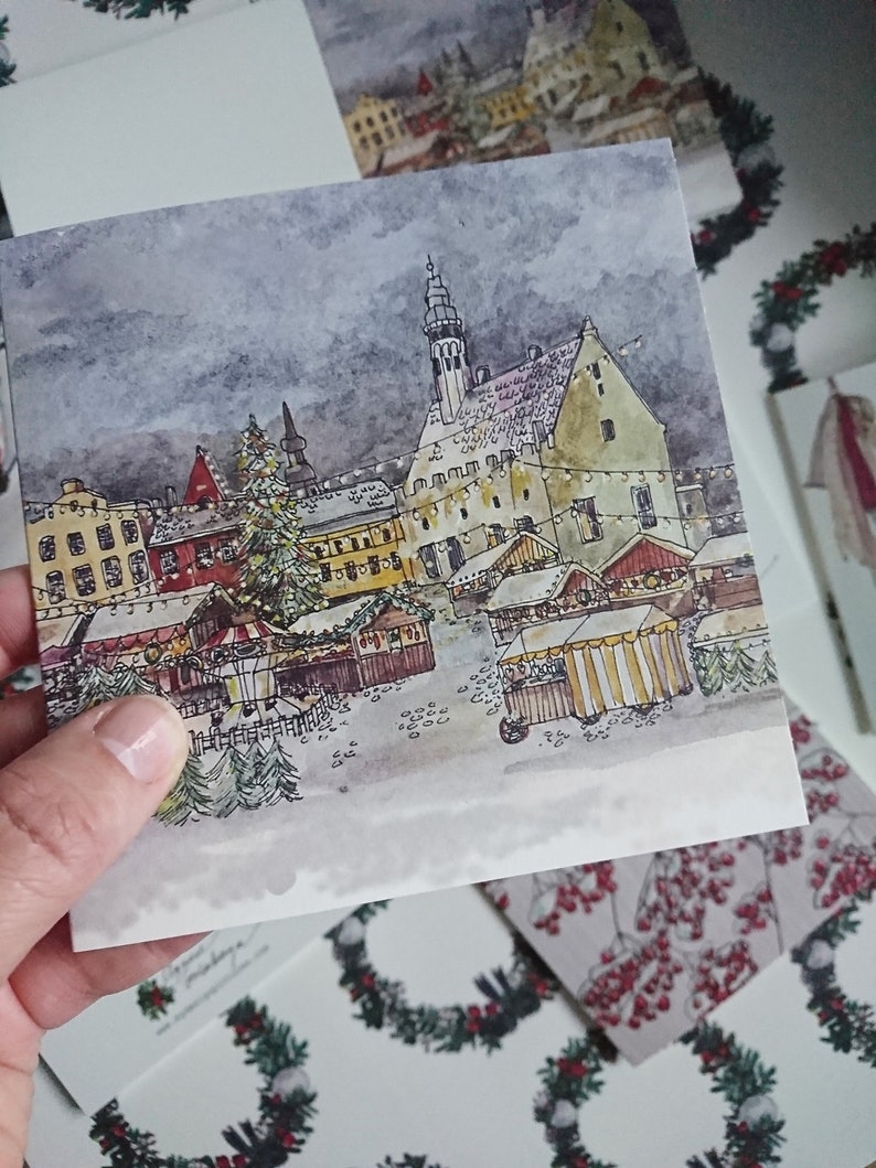May include: A watercolor painting of a European Christmas market scene with a tall church steeple in the background. The market is filled with wooden stalls and decorated with twinkling lights. There is a large Christmas tree in the center of the market.