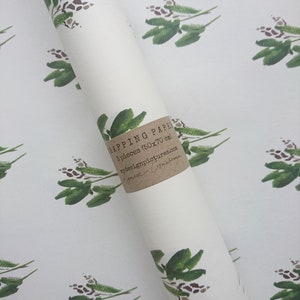 May include: A roll of white wrapping paper with a green floral pattern. The paper is labeled "Wrapping Paper 3 pieces (50x70 cm)  mydesignpictures.com Agnes Gr&ouml;nberg"