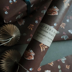 May include: A roll of brown wrapping paper with a squirrel and floral pattern. The paper is labeled "Wrapping Paper 3 pieces (50x70 cm) by designpictures.com".