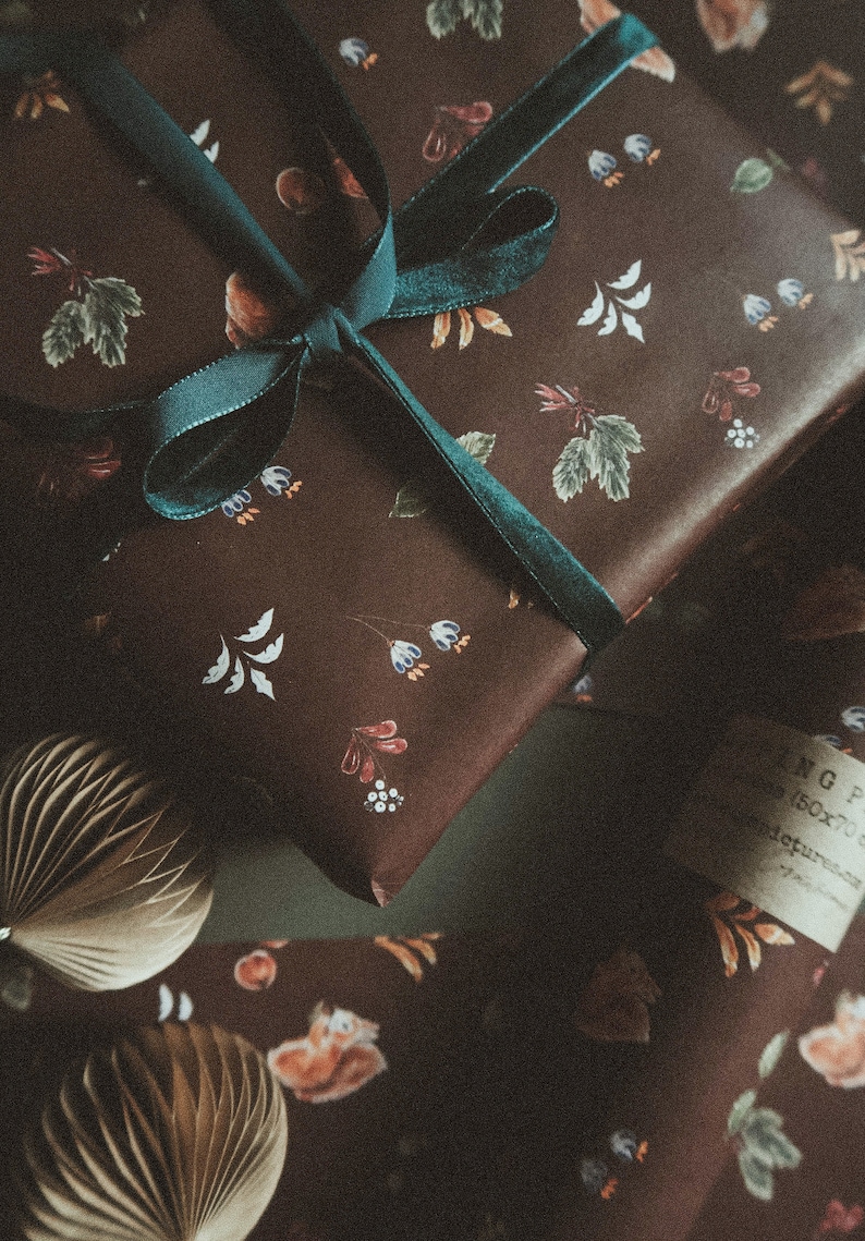 May include: A brown gift box with a teal ribbon tied in a bow. The box is wrapped in paper with a floral pattern.
