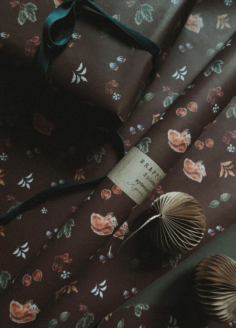 May include: A roll of brown wrapping paper with a squirrel and leaf pattern. The paper is labeled "WRAPPIN 3 pieces mydesign" and is partially unrolled. A brown paper fan is on top of the paper.