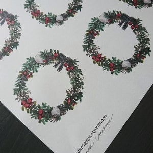 May include: A sheet of white wrapping paper with a repeating pattern of green wreaths with red berries and white ornaments. The paper is signed "mydesignpictures.com Agnes Cr&iacute;nberg&oslash;".