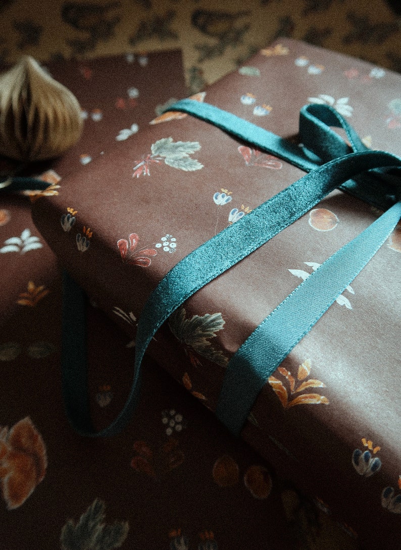 May include: A brown gift box with a teal ribbon tied in a bow. The box is wrapped in paper with a floral pattern.