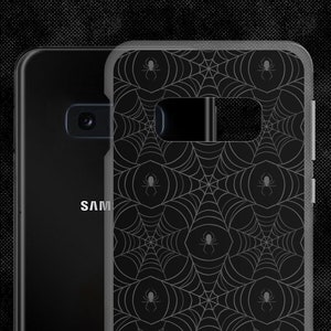 May include: Black phone case with a spiderweb pattern and small spiders. The case is made of clear plastic and has a black background.