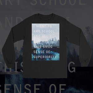 May include: Black long-sleeve shirt with a white graphic print that reads "I went to art school and all I got was this smug sense of superiority". The graphic is set against a blue and white background.