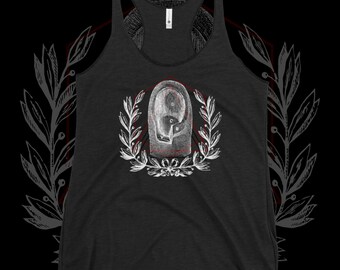 May include: Dark gray tank top with a white and red graphic. The graphic features a stylized design of a face within a laurel wreath. The tank top has a racerback design and a scoop neck.