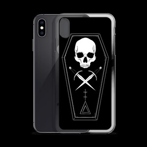 Puede incluir: Carcasa de tel&eacute;fono negra con un dise&ntilde;o de calavera blanca y espadas cruzadas dentro de una forma de ata&uacute;d. El dise&ntilde;o tambi&eacute;n incluye un tri&aacute;ngulo y una cruz.