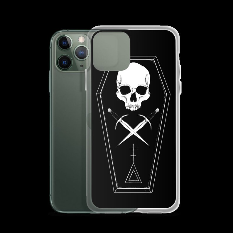Puede incluir: Una funda de tel&eacute;fono negra con un dise&ntilde;o de calavera y huesos cruzados blancos dentro de un ata&uacute;d. El dise&ntilde;o tambi&eacute;n incluye un tri&aacute;ngulo y una cruz.