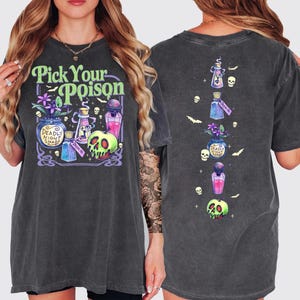 May include: Dark gray t-shirt with a colorful graphic featuring the text "Pick Your Poison". The design includes potion bottles, a skull, and the words "Deadly Night Shade". The back of the shirt has a vertical design of potion bottles and skulls.