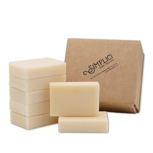 May include: A stack of eight white bars of soap in a cardboard box. The box is labeled "Simplici Soap Factory" with the address "107 Church St., Denver, TX 37033" and website "www.simplici.com".
