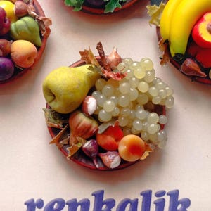 May include: Close-up of several miniature fruit arrangements. Each arrangement is in a small, red dish and includes grapes, pears, peaches, and other fruits. The word "renkalik" is printed in blue.