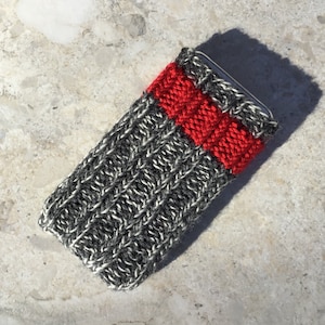 May include: A gray and white knitted phone case with a red stripe across the middle.
