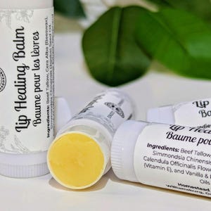 May include: Four white tubes of lip balm with yellow balm inside. The tubes are labelled "Lip Healing Balm" and "Baume pour les lèvres". The ingredients are listed on the tubes.