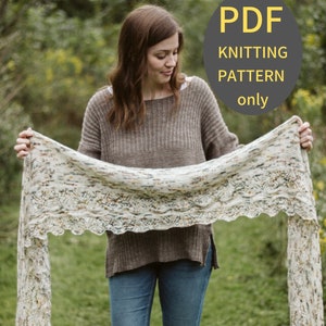 May include: A woman holds a white, cream, and brown knitted scarf with a lacy edge. The scarf is long and flowing. The text "PDF Knitting Pattern only" is on a gray circle with a yellow border.