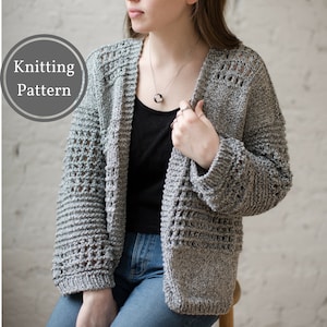 Peut inclure: Un cardigan gris en tricot avec un motif ajouré. Le cardigan est ouvert sur le devant et a des manches longues. Le mannequin porte le cardigan sur un débardeur noir et un jean bleu.