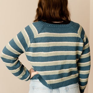 May include: A blue and green striped sweater with long sleeves and a crew neck.