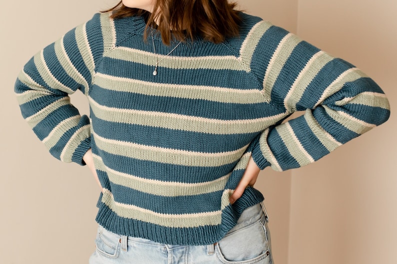 May include: A blue and green striped sweater with long sleeves. The sweater has a relaxed fit and a round neckline.