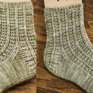 May include: A pair of knitted socks in a light green color with a textured pattern. The socks are made with a fine yarn and have a ribbed cuff.