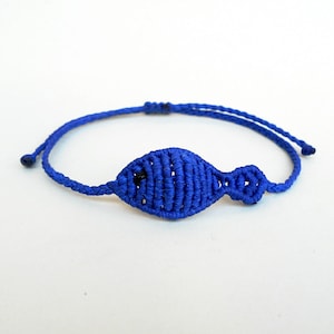 Peut inclure: Un bracelet d'amitié bleu avec un charme de poisson noué.