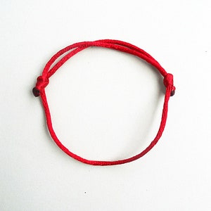 May include: A red string bracelet with two knots at the ends.