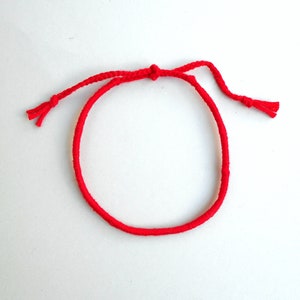 May include: A red string bracelet with a simple knot closure.