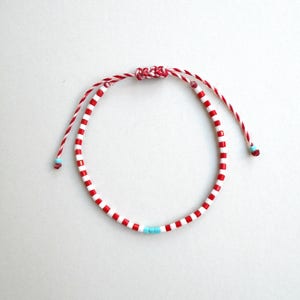 May include: Red and white striped beaded bracelet with a turquoise accent bead.
