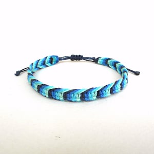 May include: A blue, green, and black braided friendship bracelet with a knotted closure.