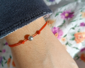 May include: A red string bracelet with a silver bead.