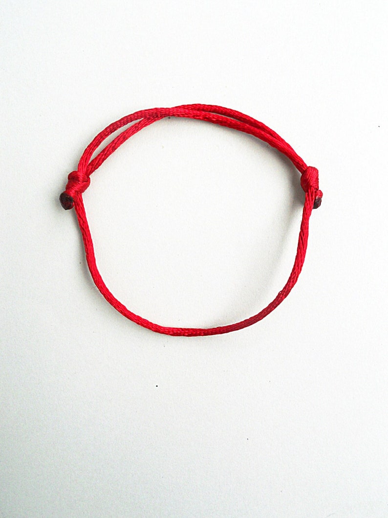 May include: A red string bracelet with two knots at the ends.