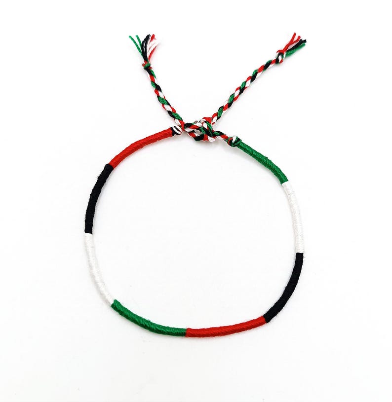 May include: A braided friendship bracelet with the colors of the United Arab Emirates flag: green, white, black, and red.