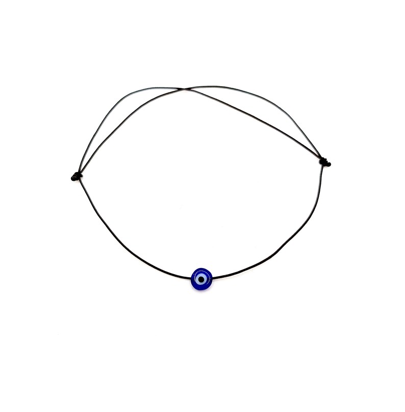 Puede incluir: Un collar sencillo de cord&oacute;n negro con un dije azul de ojo turco.