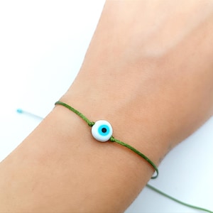 Onda ögat-armband: Gult snöre, vit glaspärlamulett, skyddande talisman, energibalanserande gåva
