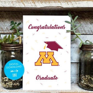 Puede incluir: Una tarjeta de graduación con la palabra "Felicidades" en una fuente burdeos, un birrete granate y la palabra "Graduado" debajo. La tarjeta presenta el logotipo de la Universidad de Minnesota en oro y granate.